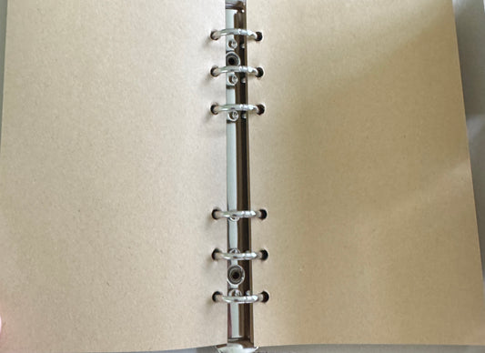 Open notebook with tan paper and metal rings.
