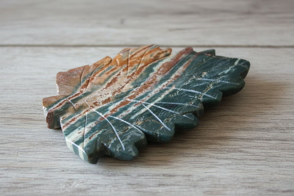 Green Jasper carving, hand tooled leaf shaped trinket dish Greens, rust colors on a table 
