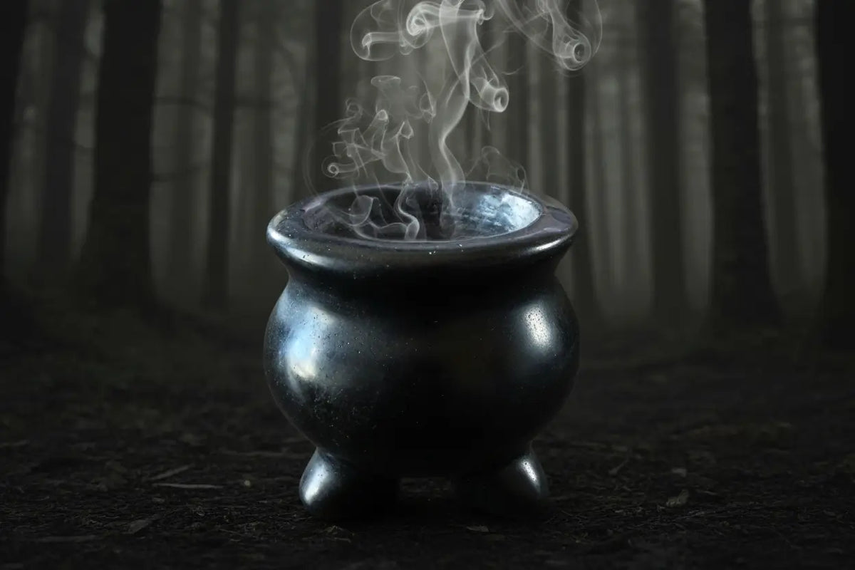 Black obsidian cauldron in a dark forest wtih smoke 
