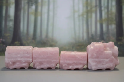 pink opal hand carved crystal four piece train set. muted forest behind 