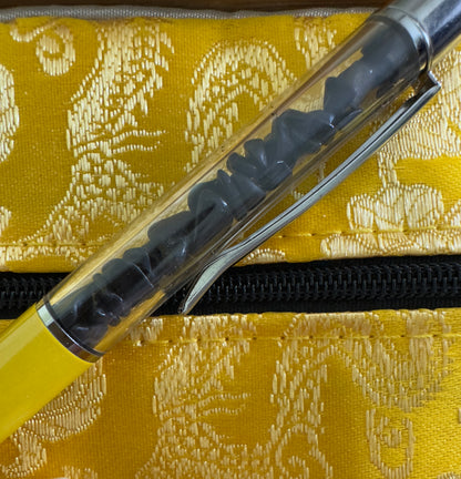 Yellow pen with black stones inside, resting on patterned yellow fabric.