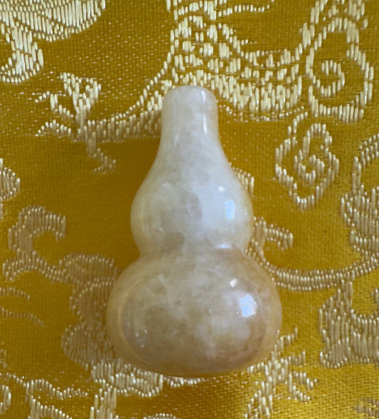 Light yellow jade gourd on patterned yellow fabric.