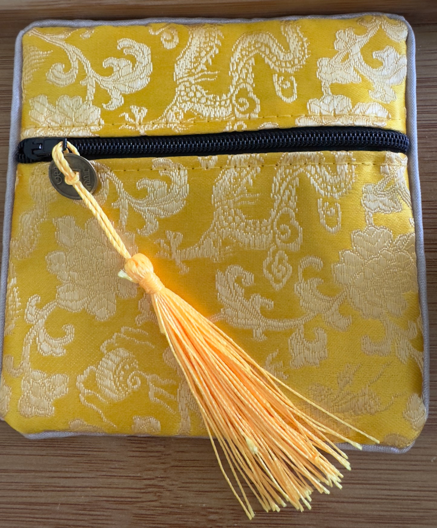 Yellow patterned fabric pouch with tassel.
