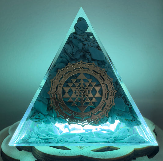 Illuminated pyramid with turquoise stones and golden geometric design.
