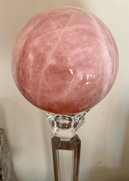 Pink crystal ball on glass stand.