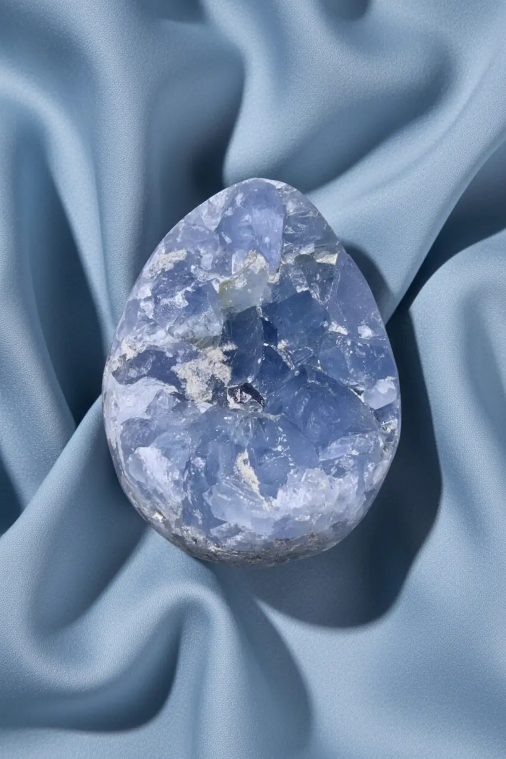 Blue celestite geode on a blue fabric
