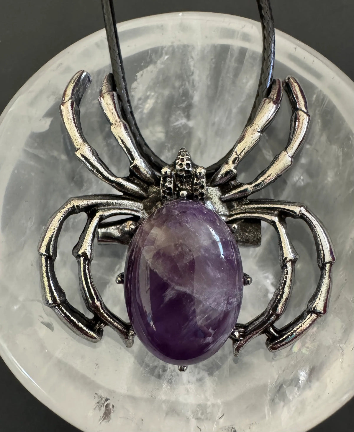 Spider-shaped pendant necklace with amethyst stone.

