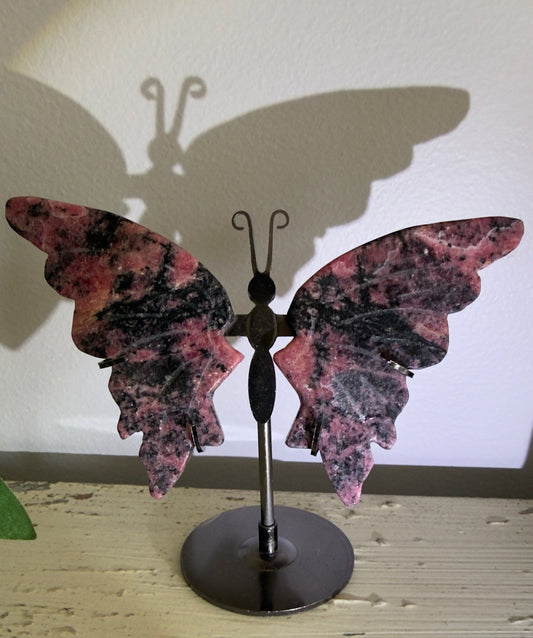 rhodonite butterfly wings carved. transformation, personal growth.pink and black wings on a black custom metal  stand