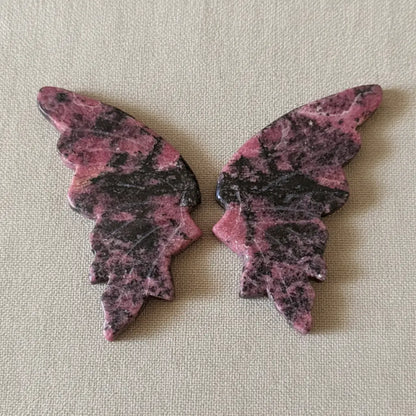 a set of pink and black rhodonite crystal carved wings