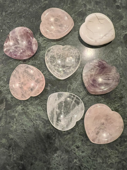 Eight polished, heart-shaped crystals on a green and black marbled surface.