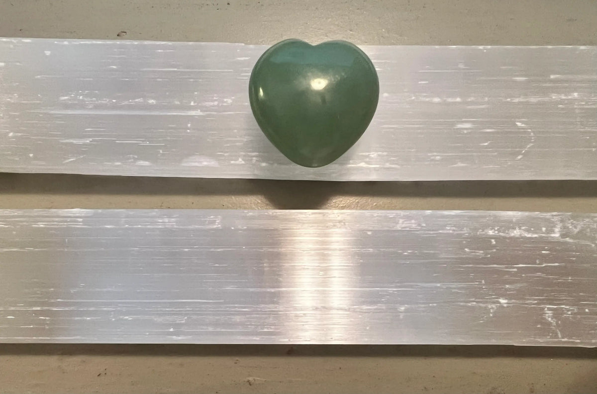Green heart-shaped stone on two selenite crystals.
