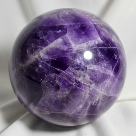 close up amethyst sphere with fractures, beautiful purples, white and likely hematite inclusions shiny platelets catching the light 