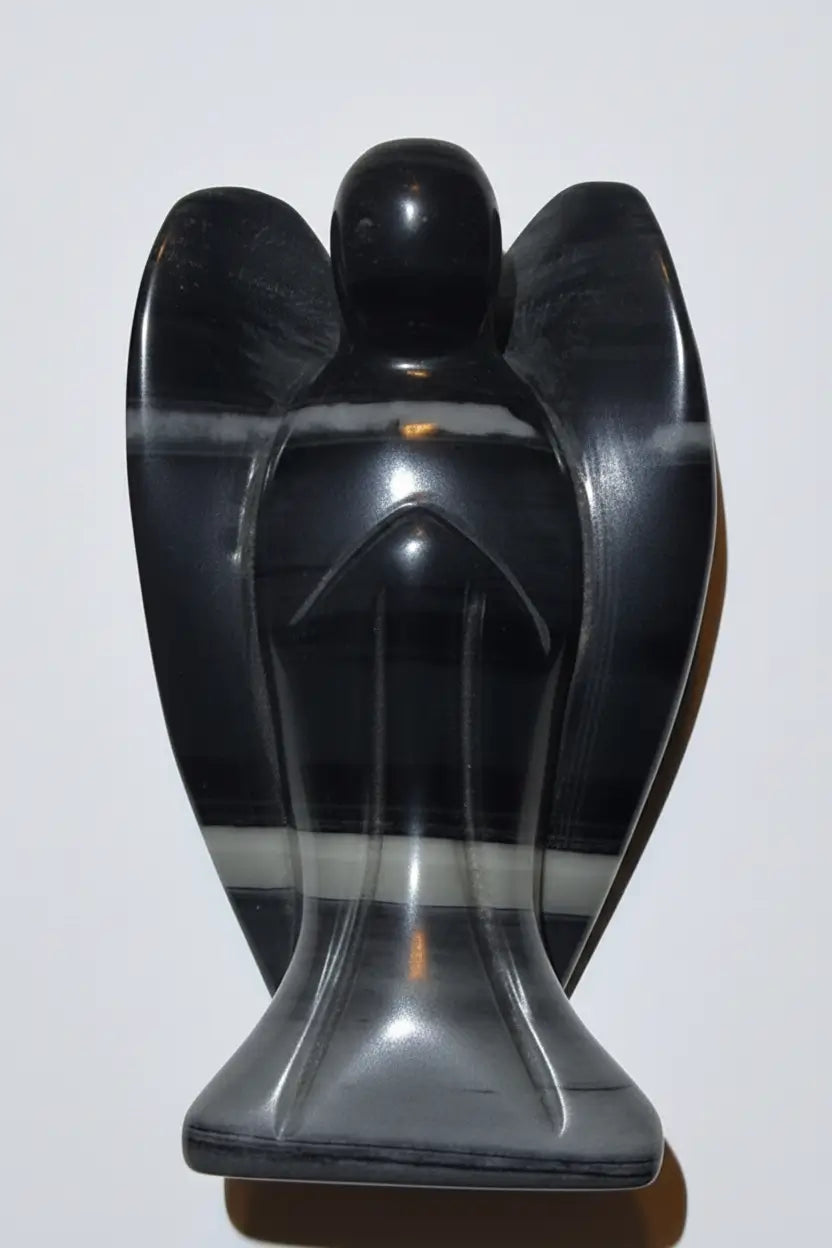Close up of TaiChi Jasper hand carved angel. Stone is banded with black, gray and off white colors 