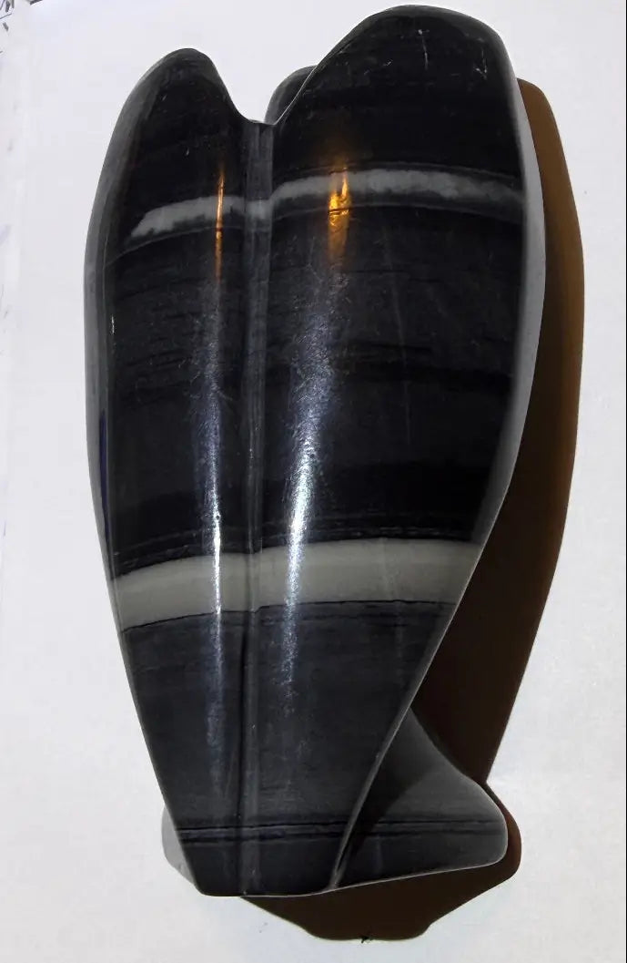 full side view taichi jasper carved angel. product has black, gray and off white bands.  black, white and grays are light and dark. 
