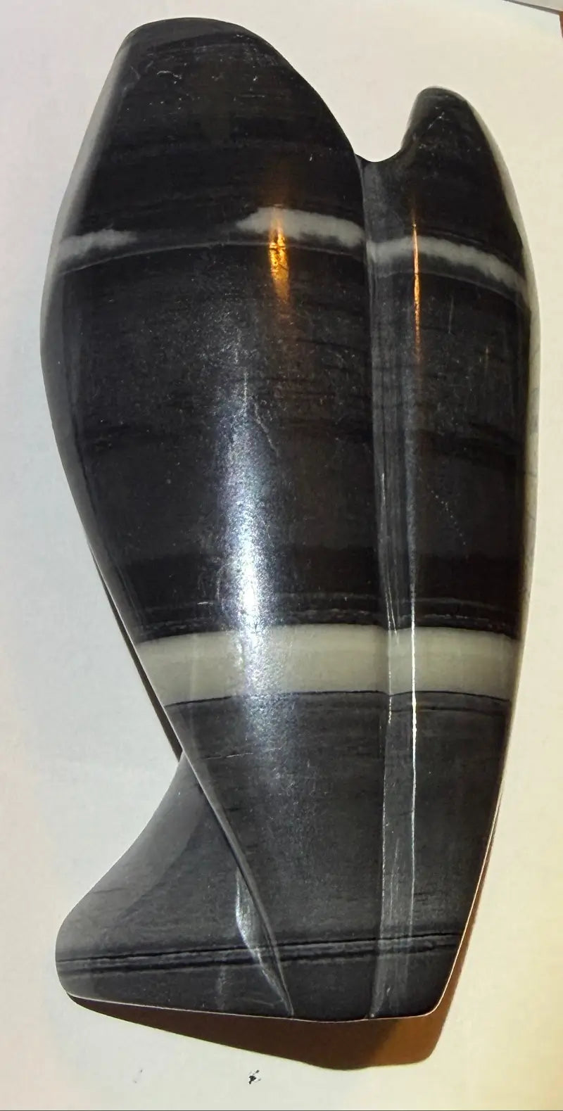 Close up back left side of TaiChi carved angel Colors Black, gray and off white banded through the piece