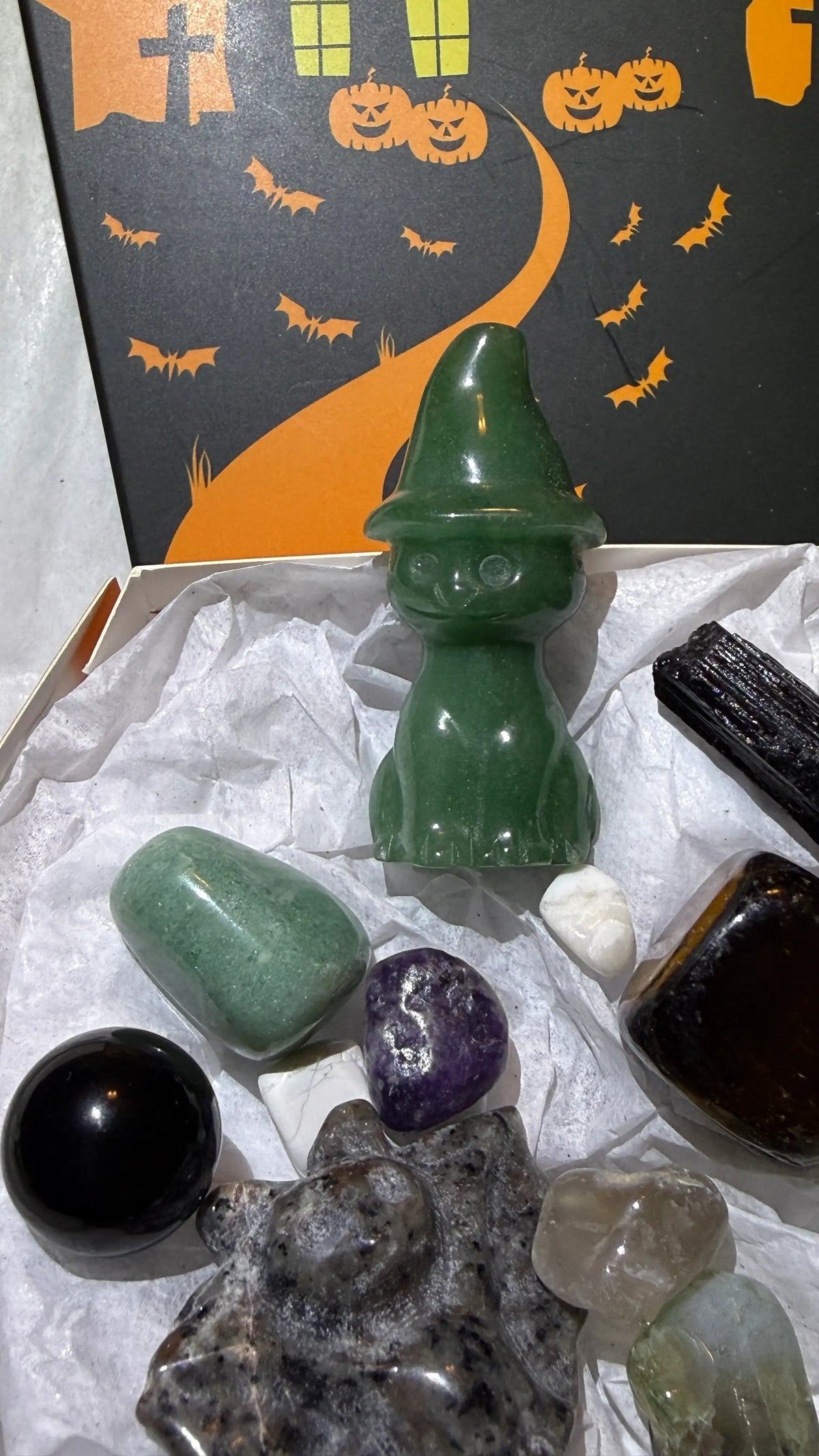 close-up photo showing green aventurine carved witch cat, bat, assorted tumbles