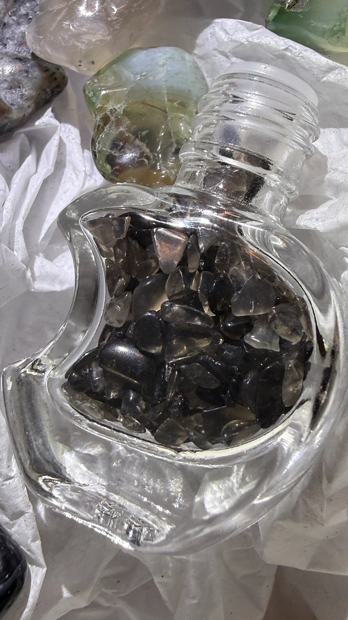 close up of crescent moon shaped glass wish bottle filled with black obsidian gravel