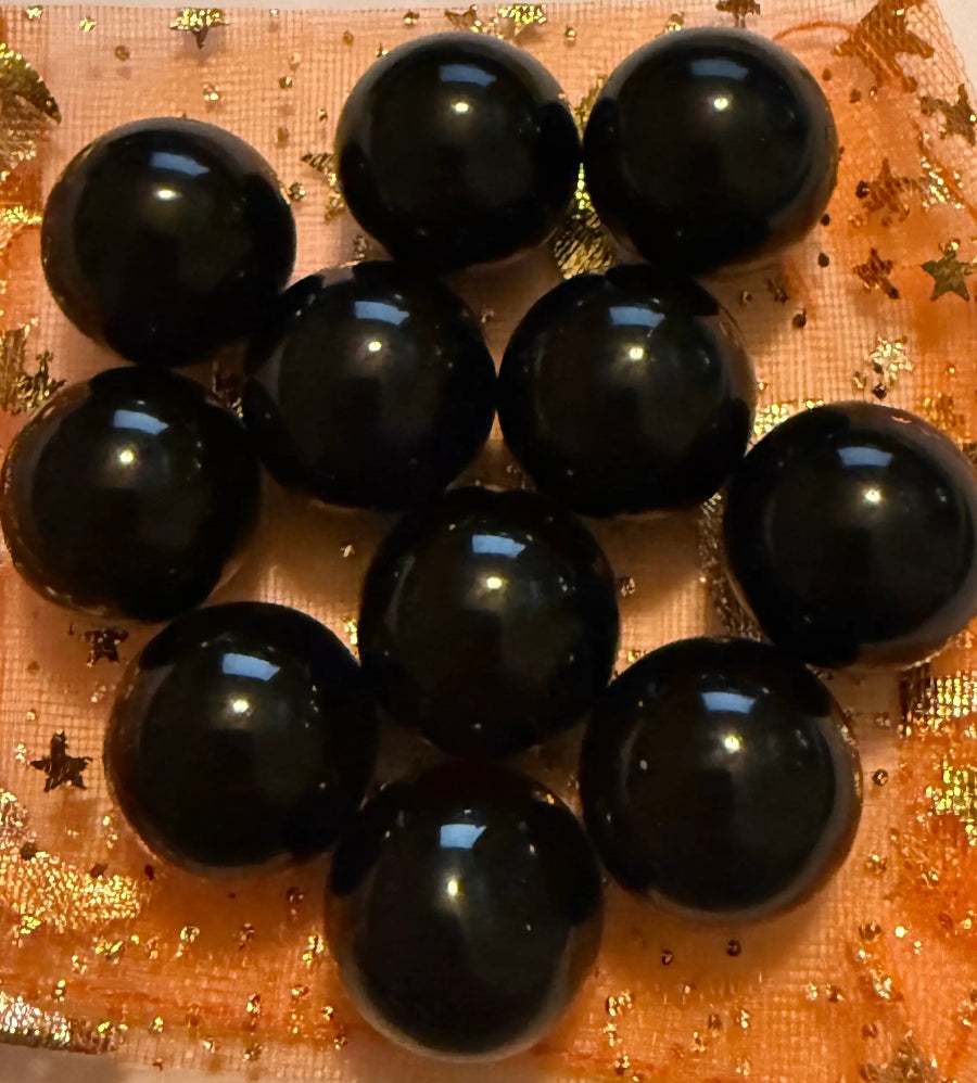 close up petite black agate spheres on an orange background