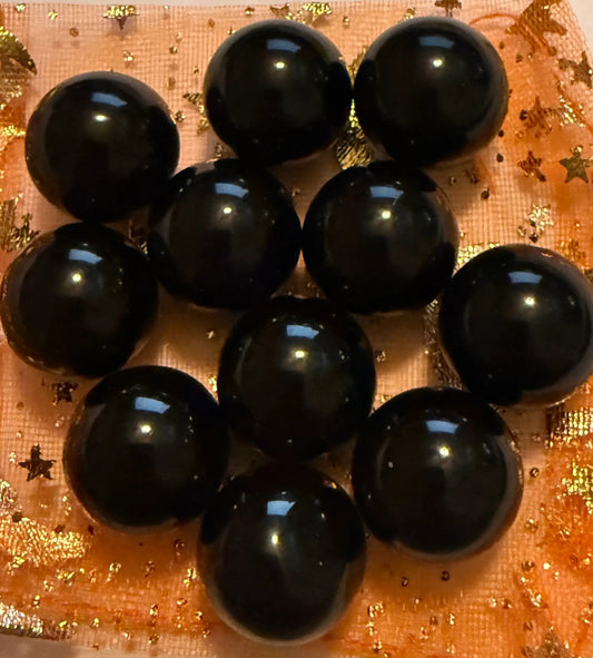 close up petite black agate spheres on an orange background