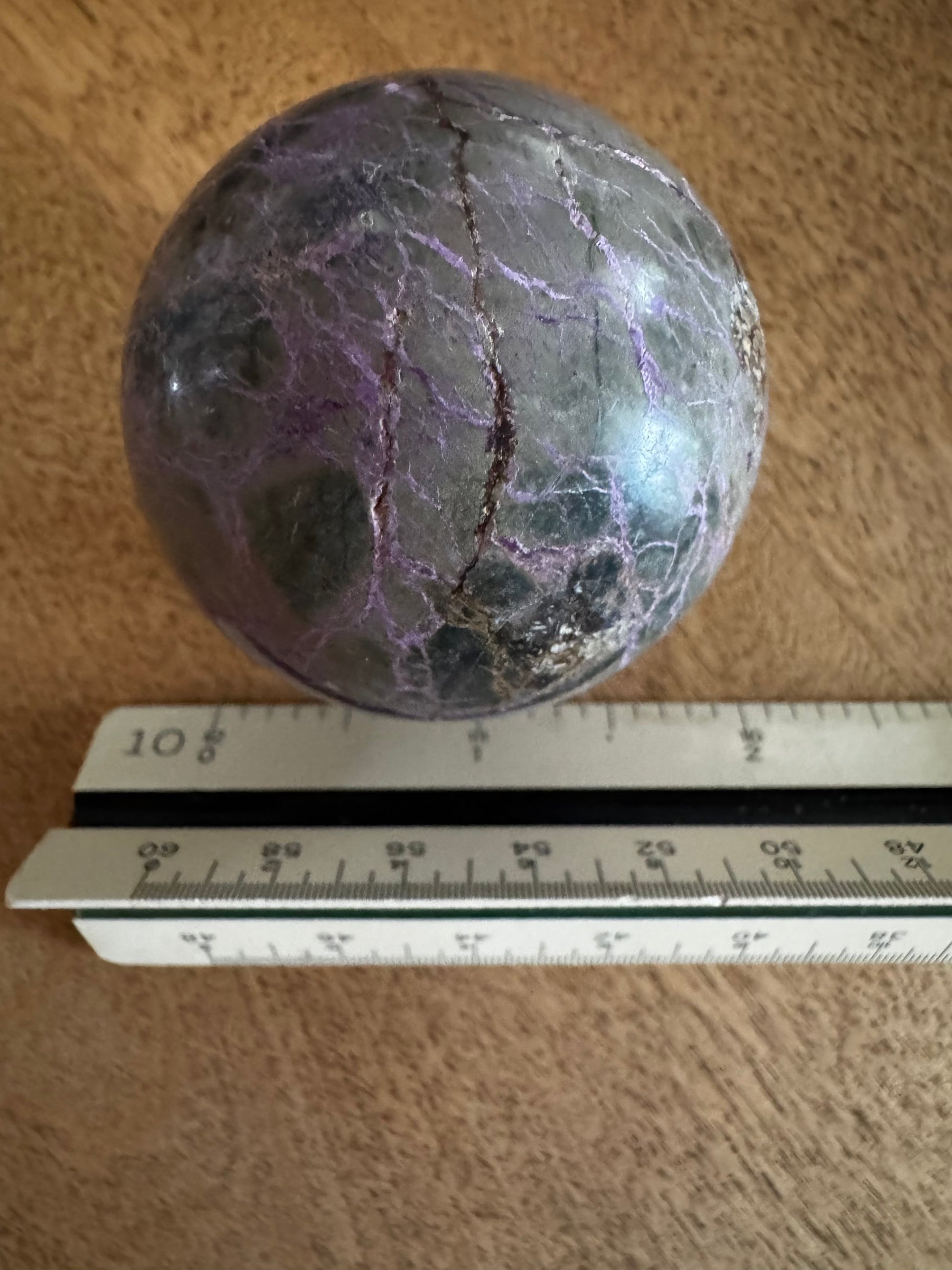 Gray and purple polished stone sphere with ruler.
