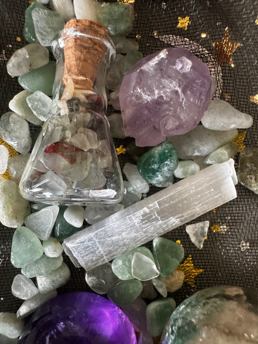 Overhead shot of crystals, including green aventurine, amethyst, selenite, and a bottle filled with stones.