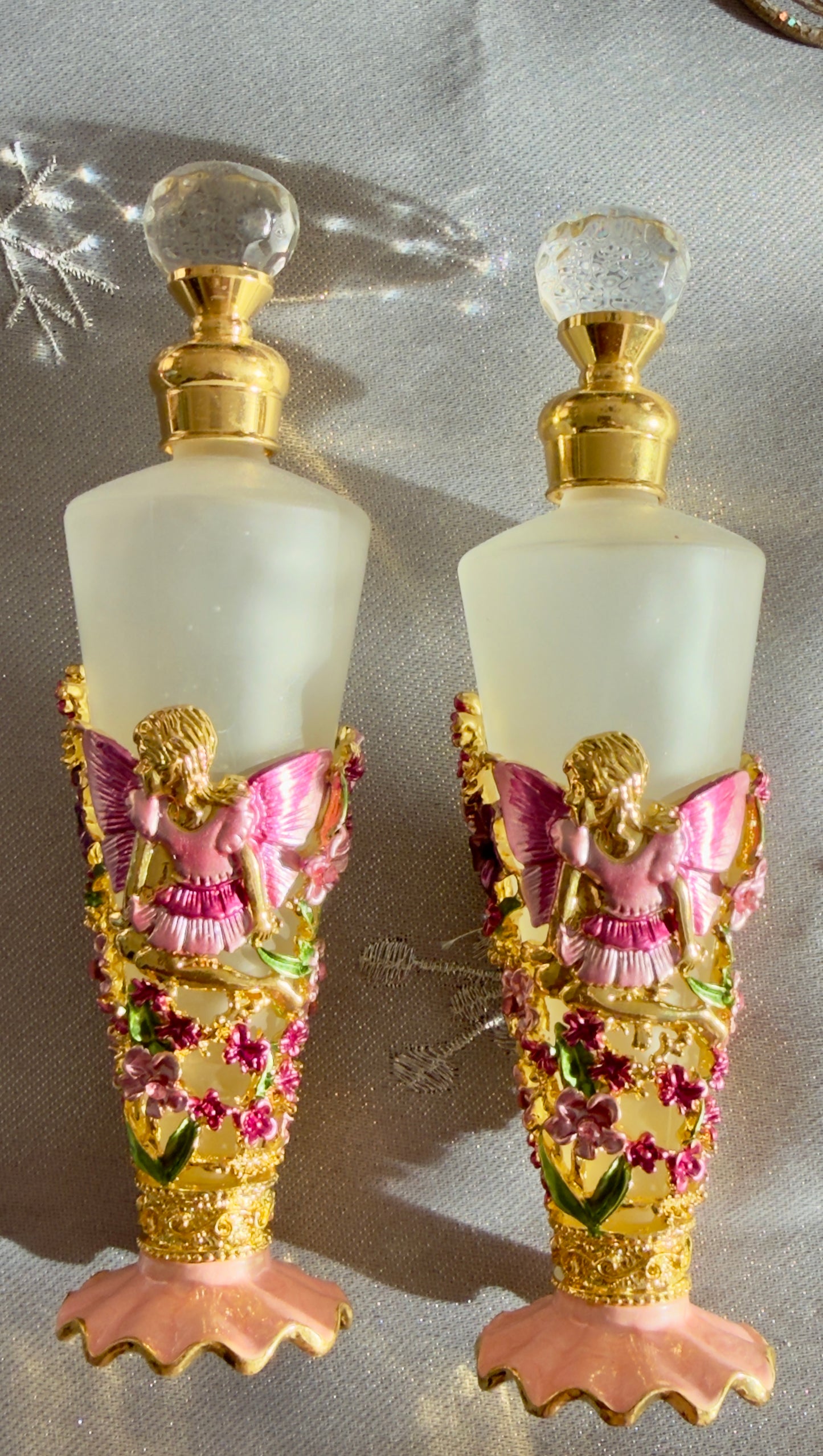 picture of frosted glass fragrance bottles with baroque pink angel design