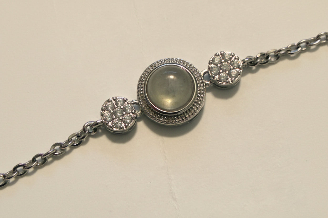 Silver bracelet with a central gemstone on a light beige background