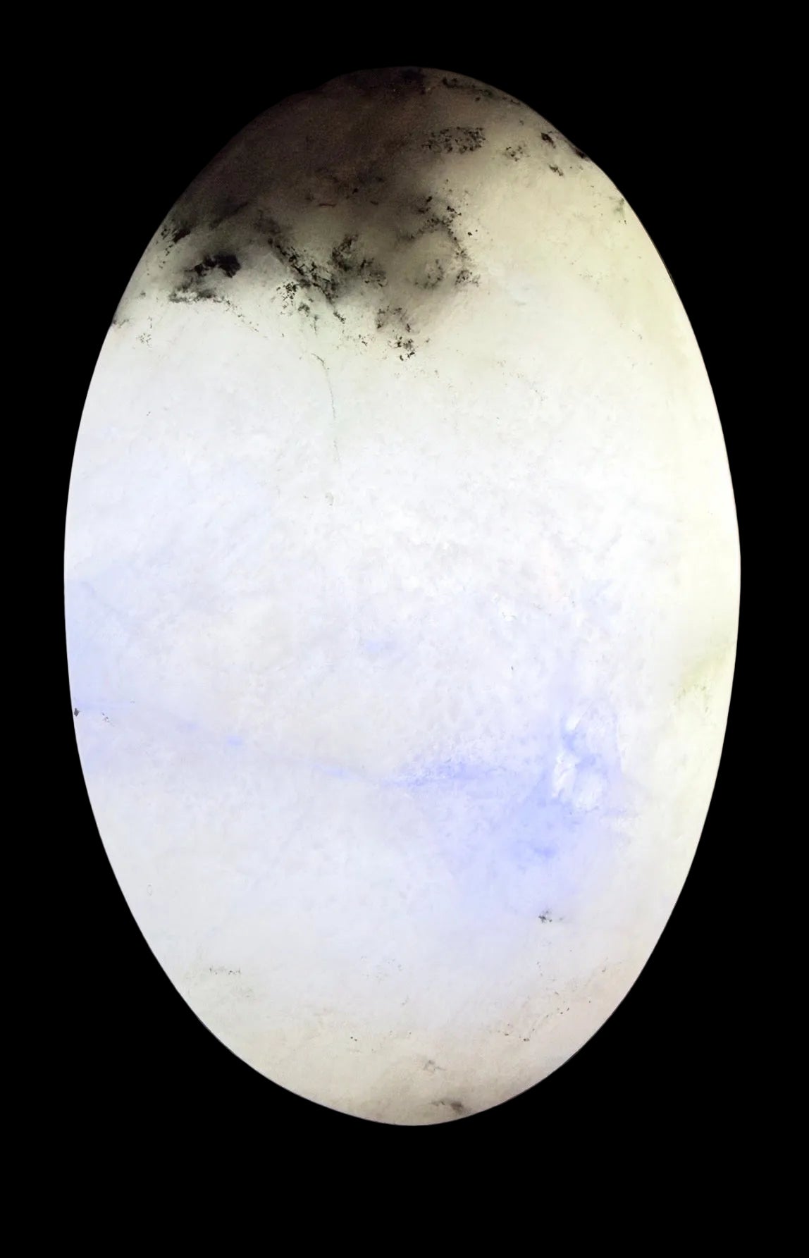 rainbow moonstone palm stone with caterpillar fractures and light behind