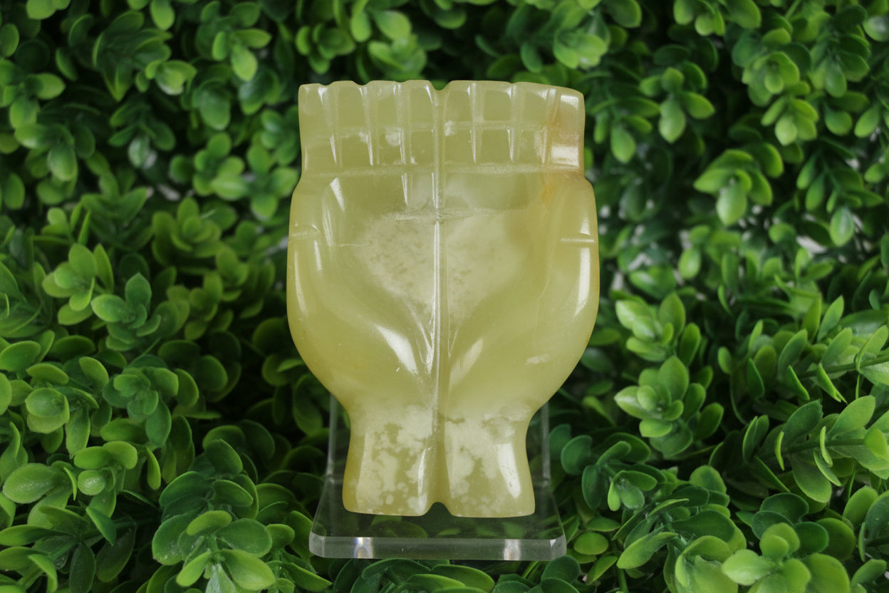 green onyx offering hands sculpture on a layer of leaves
