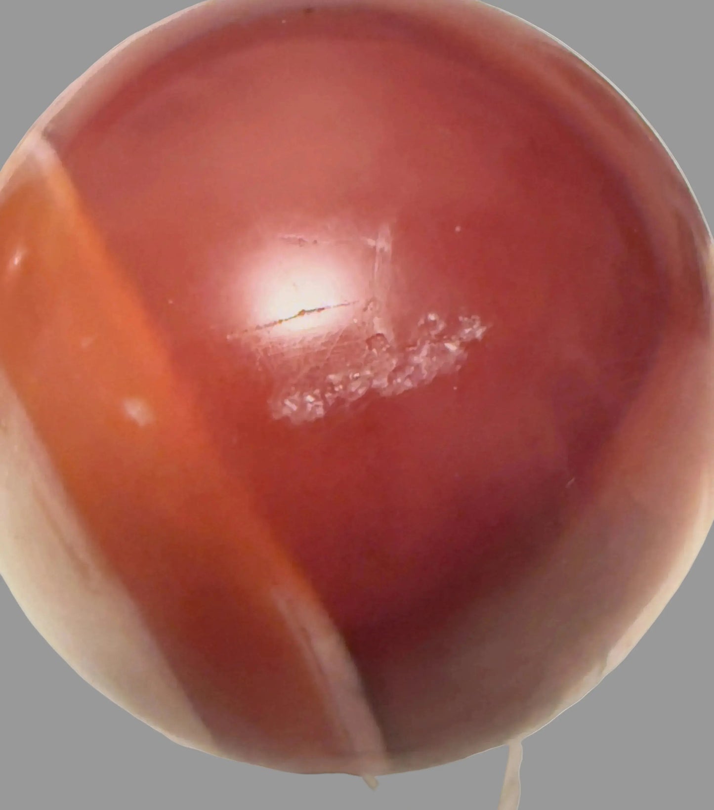 Carnelian sphere with orange banding and natural surface marks