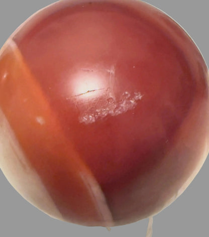 Carnelian sphere with orange banding and natural surface marks