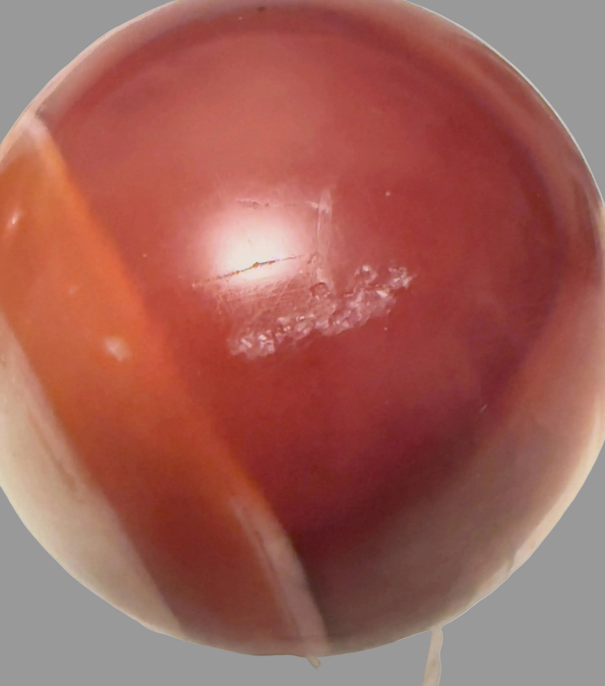 Carnelian sphere with orange banding and natural surface marks