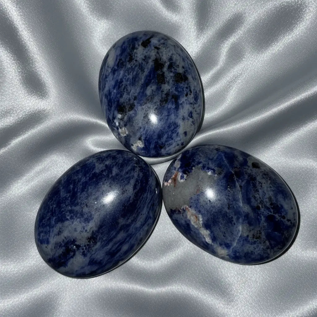 blue sodalite crystal palm stones three in photo with silver background