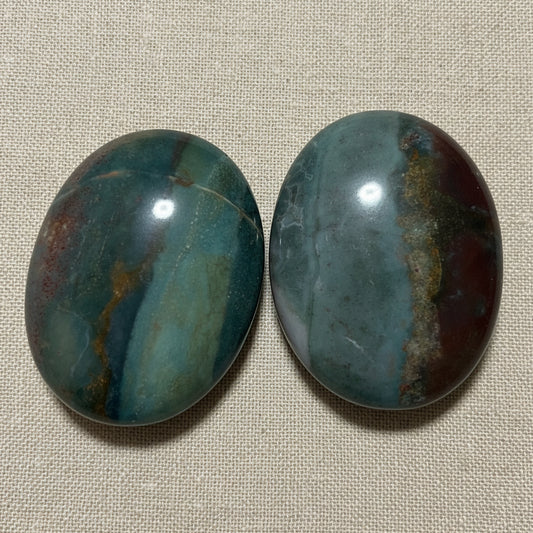close up of two ocean jasper palm stones.  beautiful greens, aqua, tan and brown colors