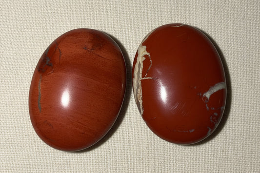 close up of two brecciated jasper polished palm stones. beautiful red/rust color
