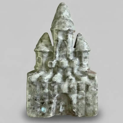 close up labradorite carved castle showing light and dark greens mixed with white inclusions 