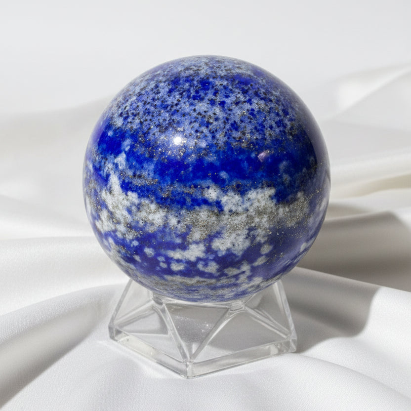 close up of a lapis lazuli polished sphere on a small stand blues are bright with the silver inclusions mica or calcite 