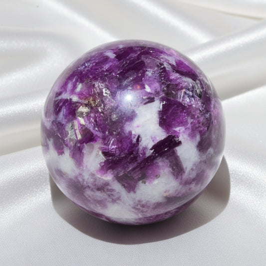 A polished lepidolite crystal sphere with prominent purple and white fluorite inclusions 