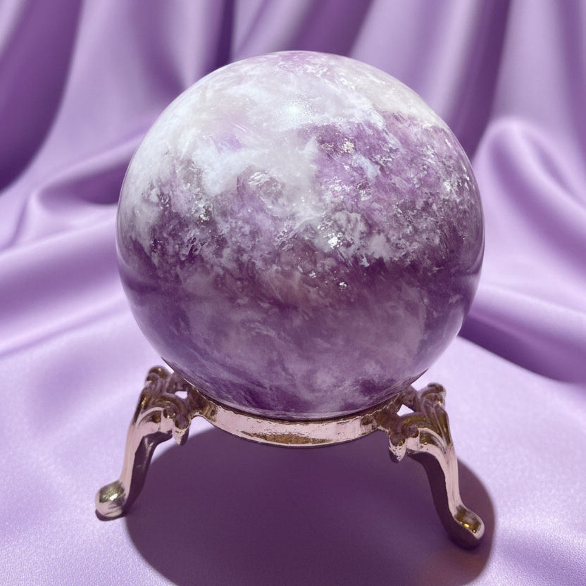 Close-up lepidolite sphere in a stand with a soft lavender background 