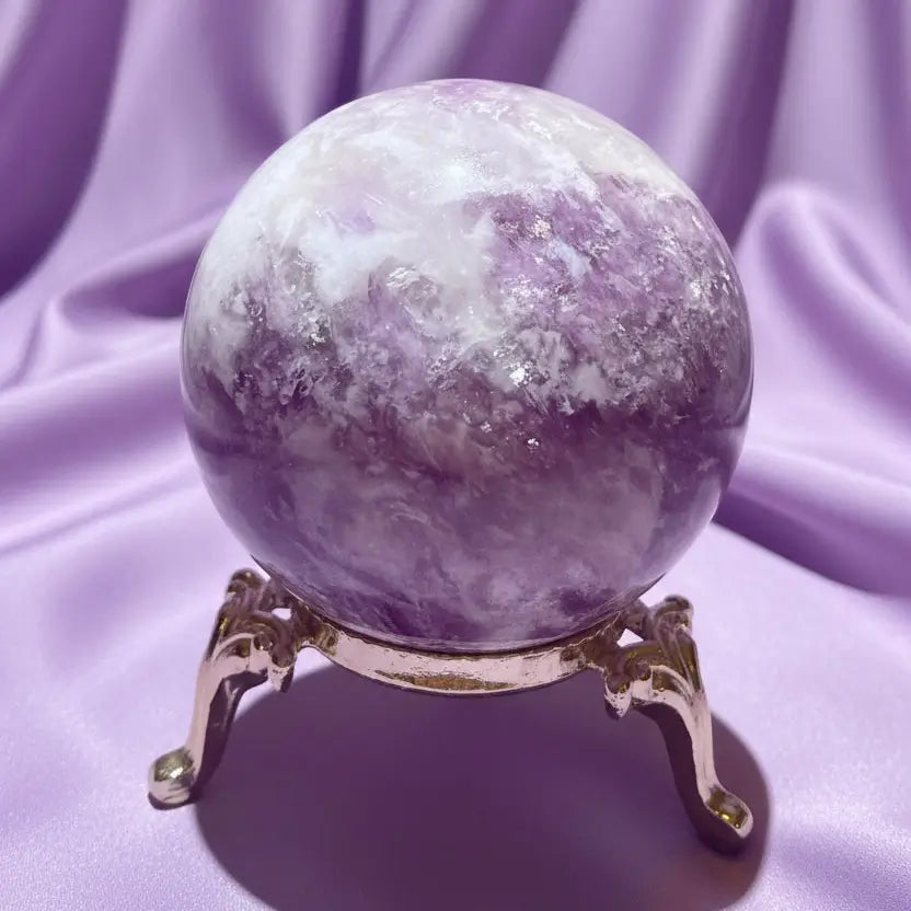 Close-up lepidolite sphere in a stand with a soft lavender background 