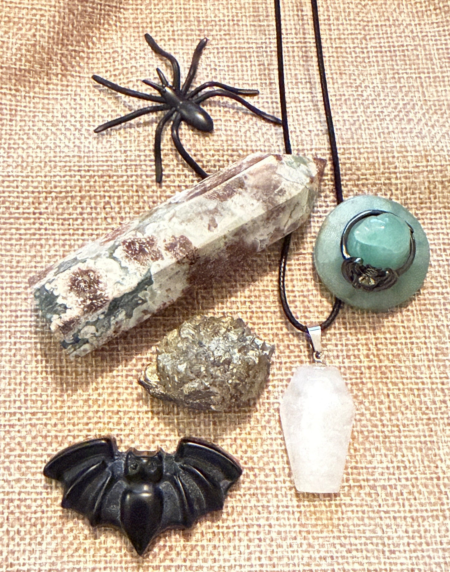 looking down at rainforest jasper hex tower, pyrite, carved black obsidian bat, carved green aventurine witch hat with bat ring (citrine stone), clear quartz carved coffin shaped necklace