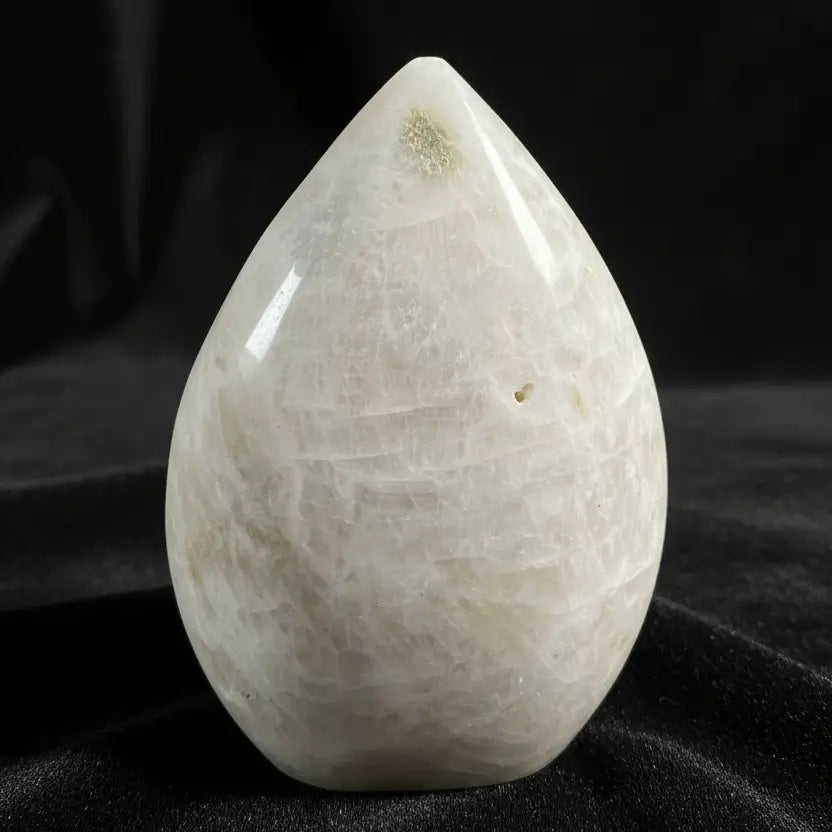 A teardrop-shaped moonstone freeform with a black background