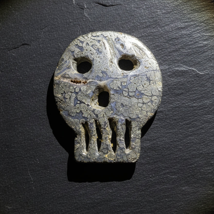 A carved pyrite skull-shaped object with eye and mouth cutouts