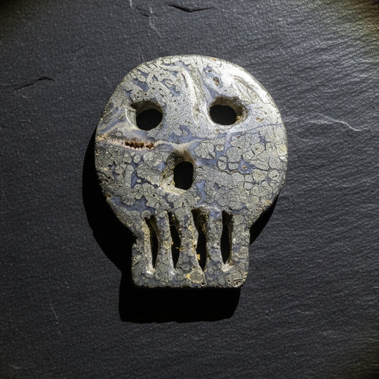 A carved pyrite skull-shaped object with eye and mouth cutouts