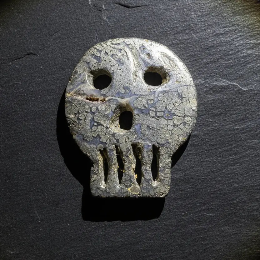 A carved pyrite skull-shaped object with eye and mouth cutouts
