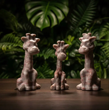 Slight side view close up of three giraffes hand carved from red vein jasper crystal bright pinks iron oxide pigments and off white  nice details smiles eyes 