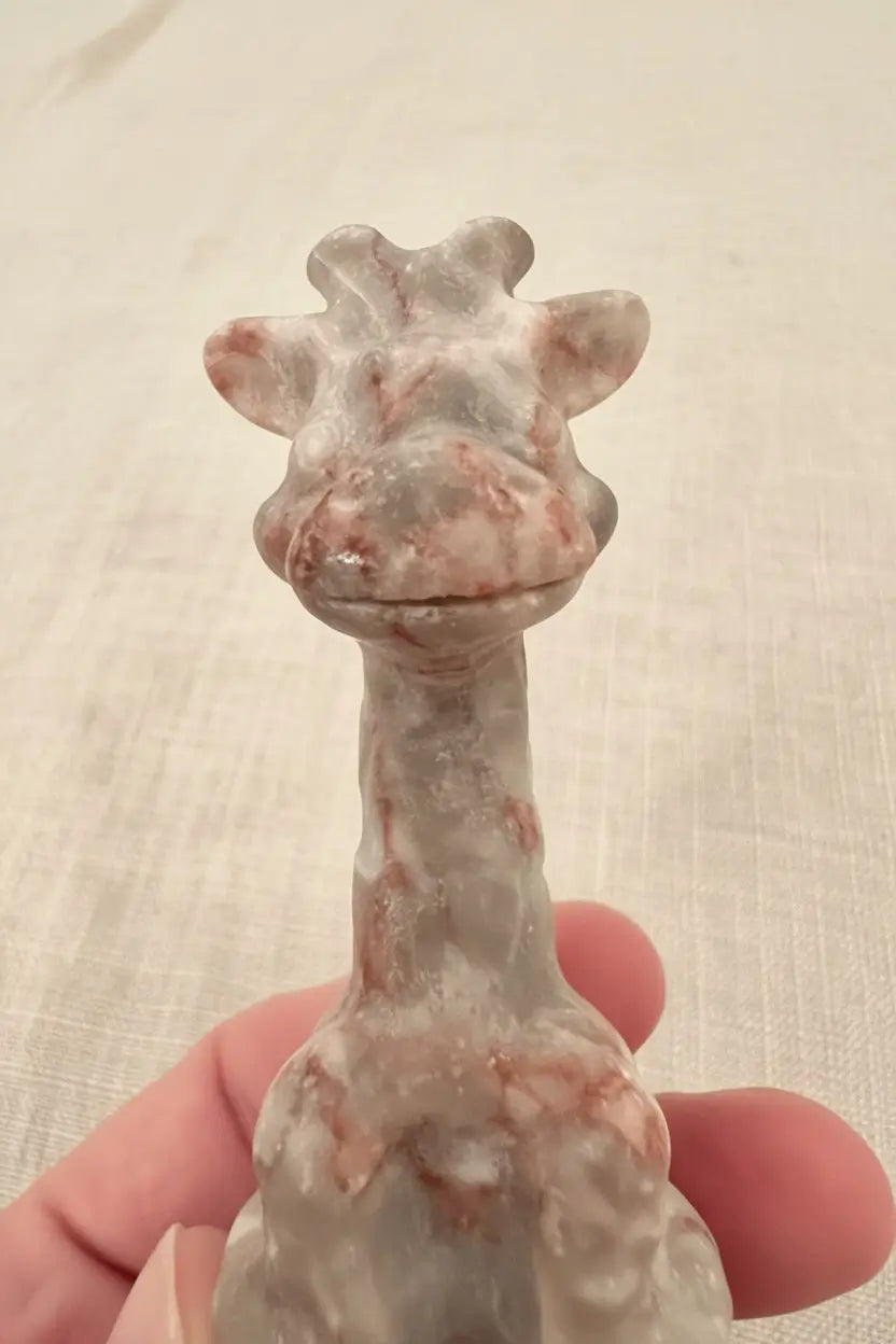 close up giraffe face and figurine  Hand carved red vein jasper crystal. pretty pinks weave through the cream color jasper
