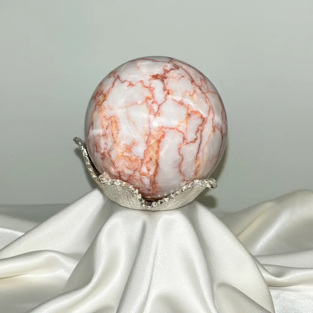 red vein jasper sphere in a silver sand off white fabric sphere is off white with red/orange veins  also known as network jasper 