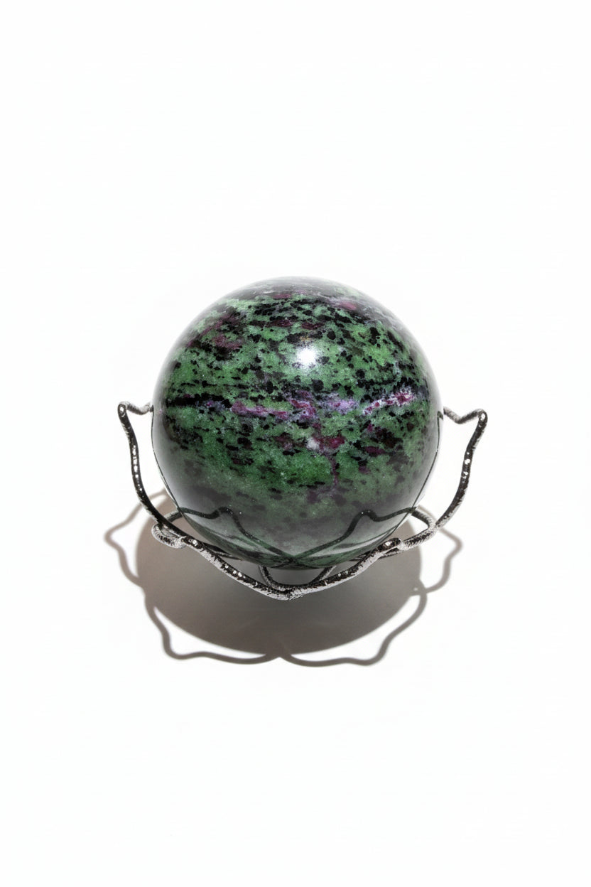 Ruby in Zoisite Sphere Bright greens and purples, speckles in a wire lotus shaped basket on a desk