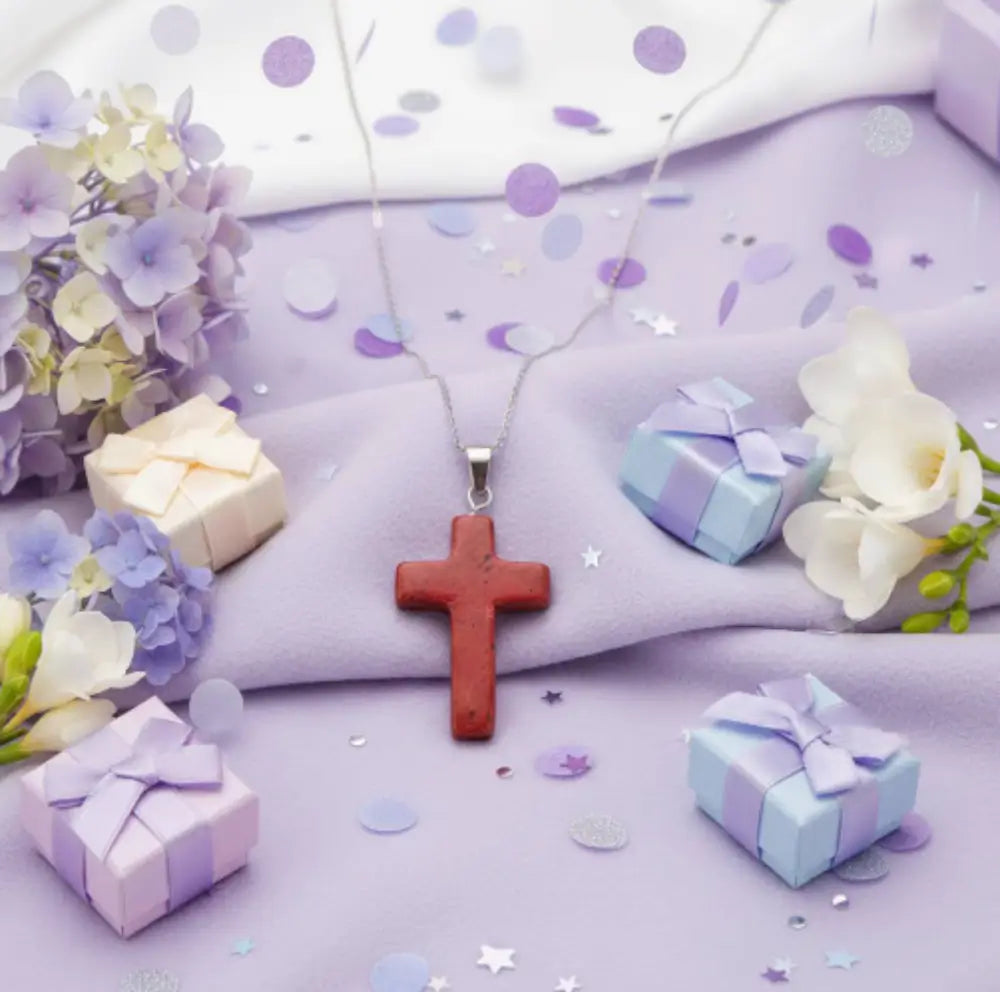 Pretty Red Jasper carved cross pendant with a lavender background lavender gift boxes and flowers 